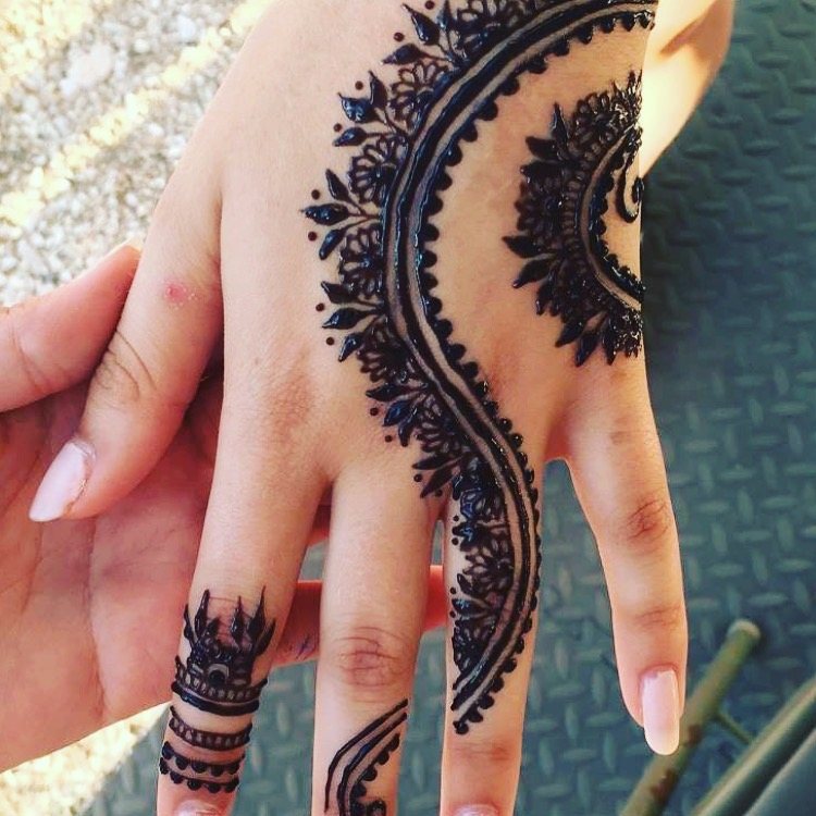 A bold flowing henna design across a hand