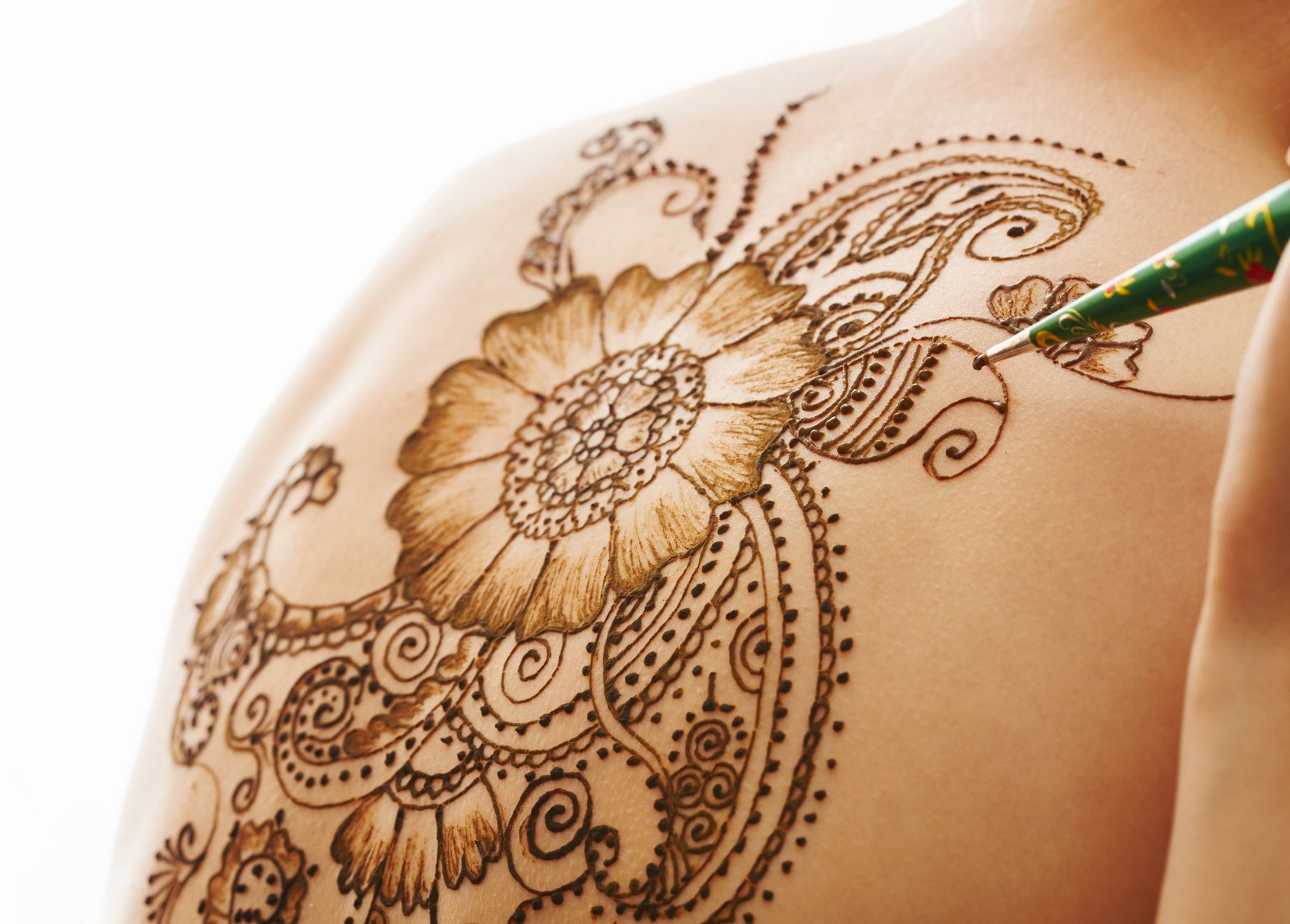 An artist adding fine details to a large floral henna design